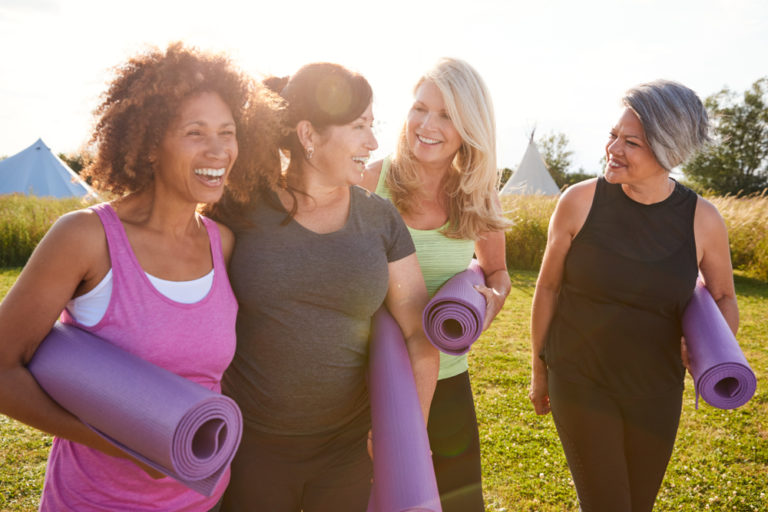Older women laughing with yoga mats