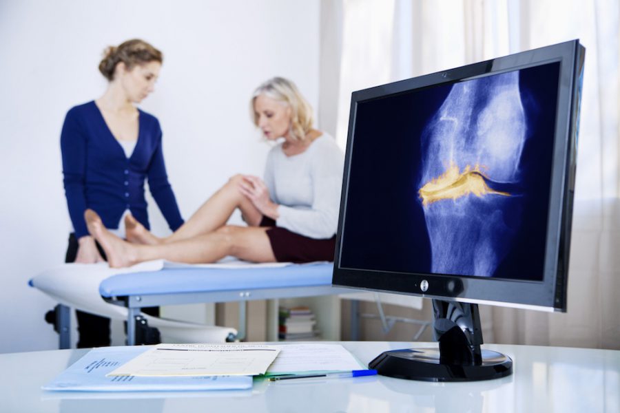 A woman and a doctor examining her knee