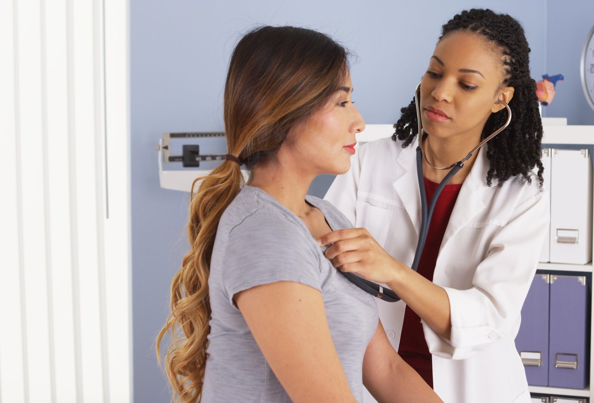 female doctor listening to female patient's heart