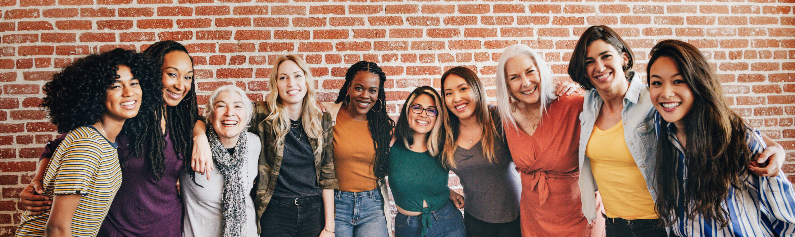 Cheerful diverse women standing in front of a red brick wall