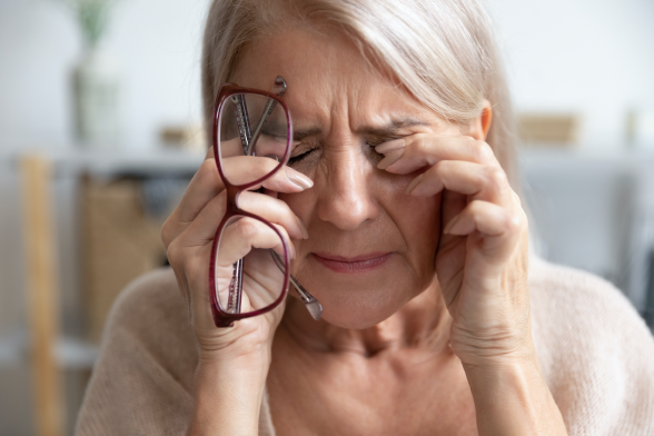 Woman holding glasses rubbing her eyes