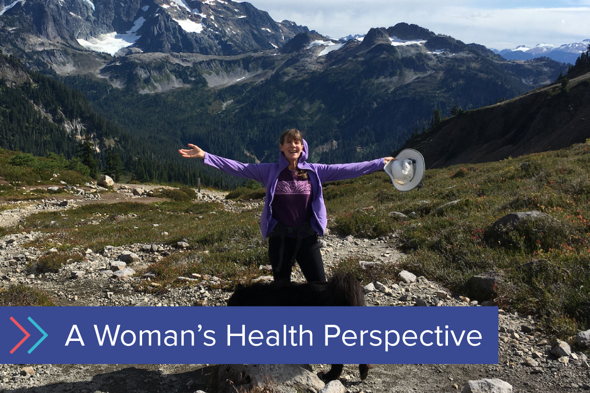 Woman hiking smiling with her arms open wide in front of mountains