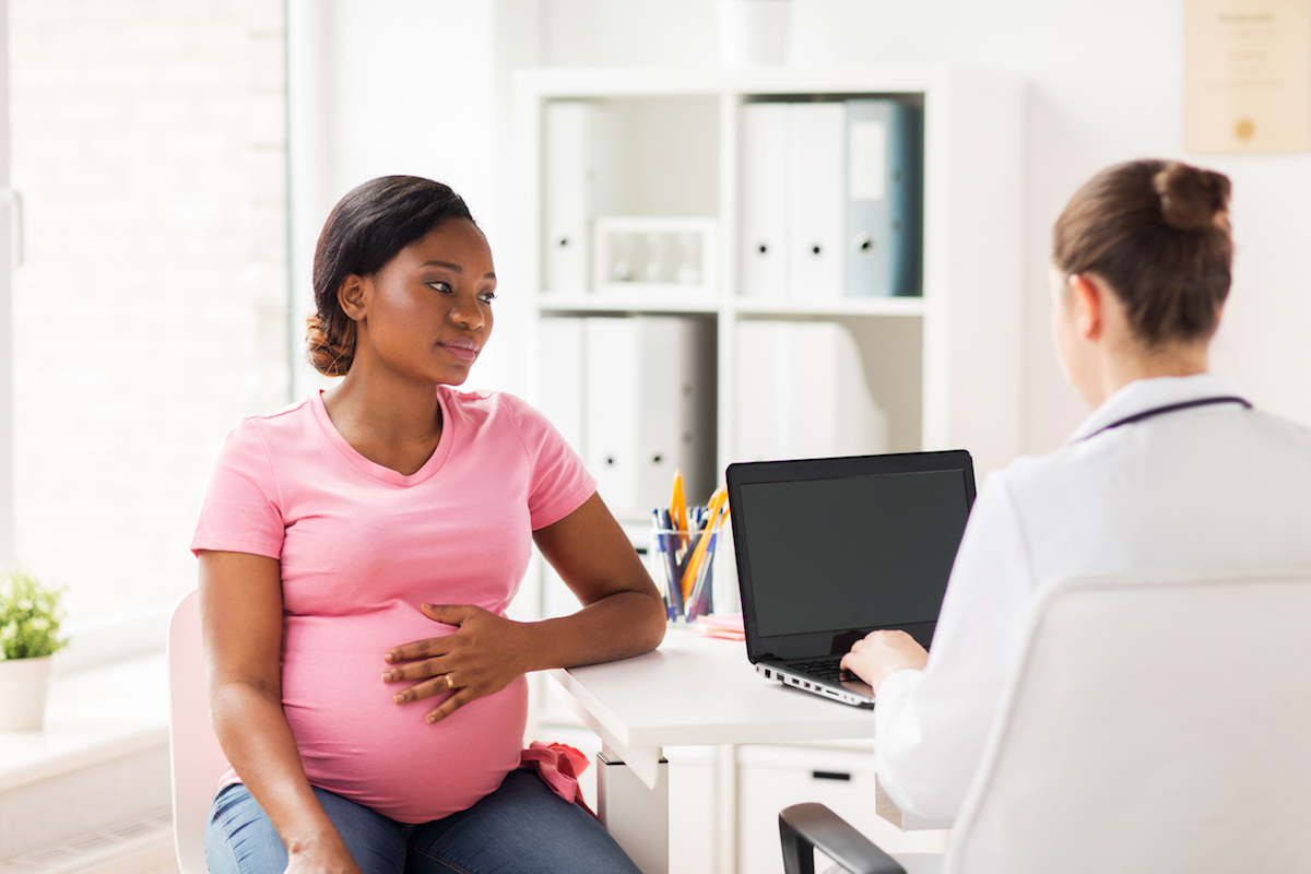 black mom pregnant with doctor at computer